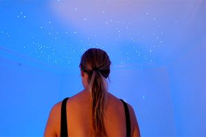 Woman standing in a float room under a starlight ceiling